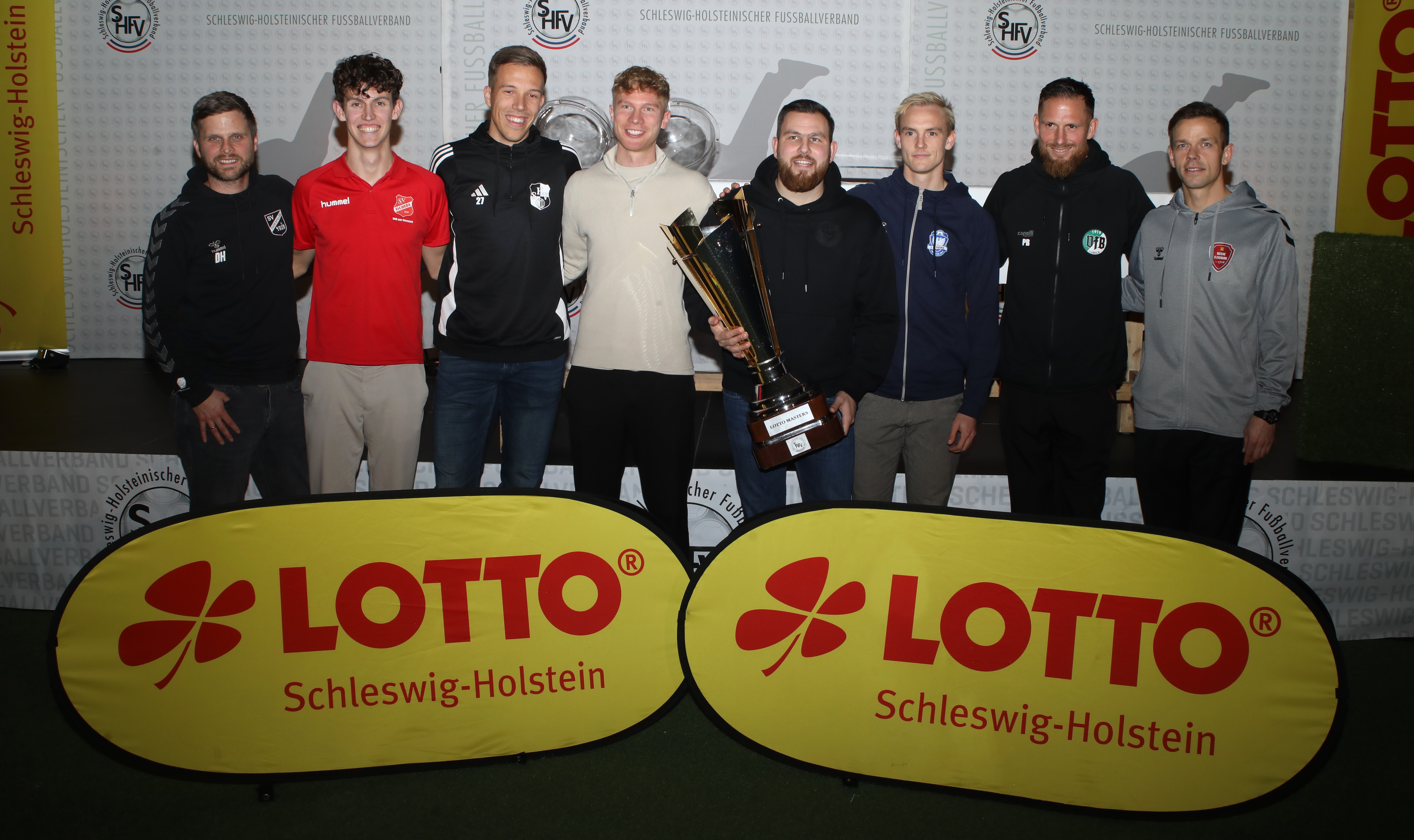 Vertreter der acht Teilnehmer nach der Auslosung in Malente (von links): Dirk Hellmann (SV Todesfelde), Silas Meyer (SV Eichede), Jonah Gieseler (Heider SV), Finn Wirlmann (Holstein Kiel U23), Nico Soranno (Kilia Kiel), Johan Berger (Phönix Lübeck), Pierre Becken (VfB Lübeck), Mads Albaek (Weiche Flensburg).